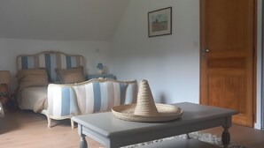 Un dormitori amb un llit, una taula de nit amb una làmpada, una cadira i un con decoratiu sobre la taula.