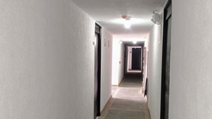 Ein schmaler, gut beleuchteter Flur mit weißen Wänden und Teppichboden, der zu einer Tür am Ende führt.