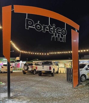 A parking area with a sign reading "Póntico mall" and several parked vehicles.