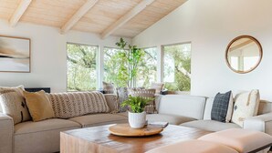 A modern living room with a sofa, coffee table, and a potted plant.