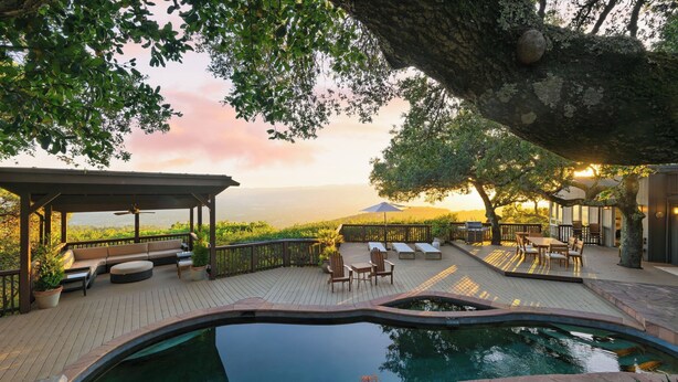 A pool area with a pergola, seating, and a view of the landscape.