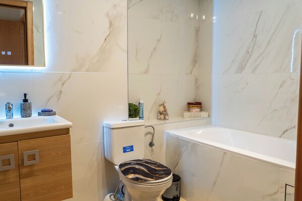 A modern bathroom with a toilet, sink, and bathtub.