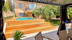Ein Außenbereich mit Terrasse, Pool und Sitzgelegenheiten.