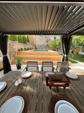 Un patio exterior con piscina, terraza de madera y zona de estar.