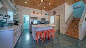 A kitchen with a central island, white cabinets, and orange stools. - 2 Homes in Gulf Village by Avantstay Sleeps 24, 2blocks to the Beach, Pool, Game Room, Patio w/ Outdoor Bar (Port Aransas)