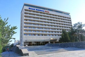 Un hotel de varios pisos con fachada plana, balcones y una entrada destacada.