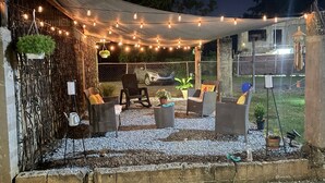 An outdoor patio area with string lights, wicker furniture, and potted plants.