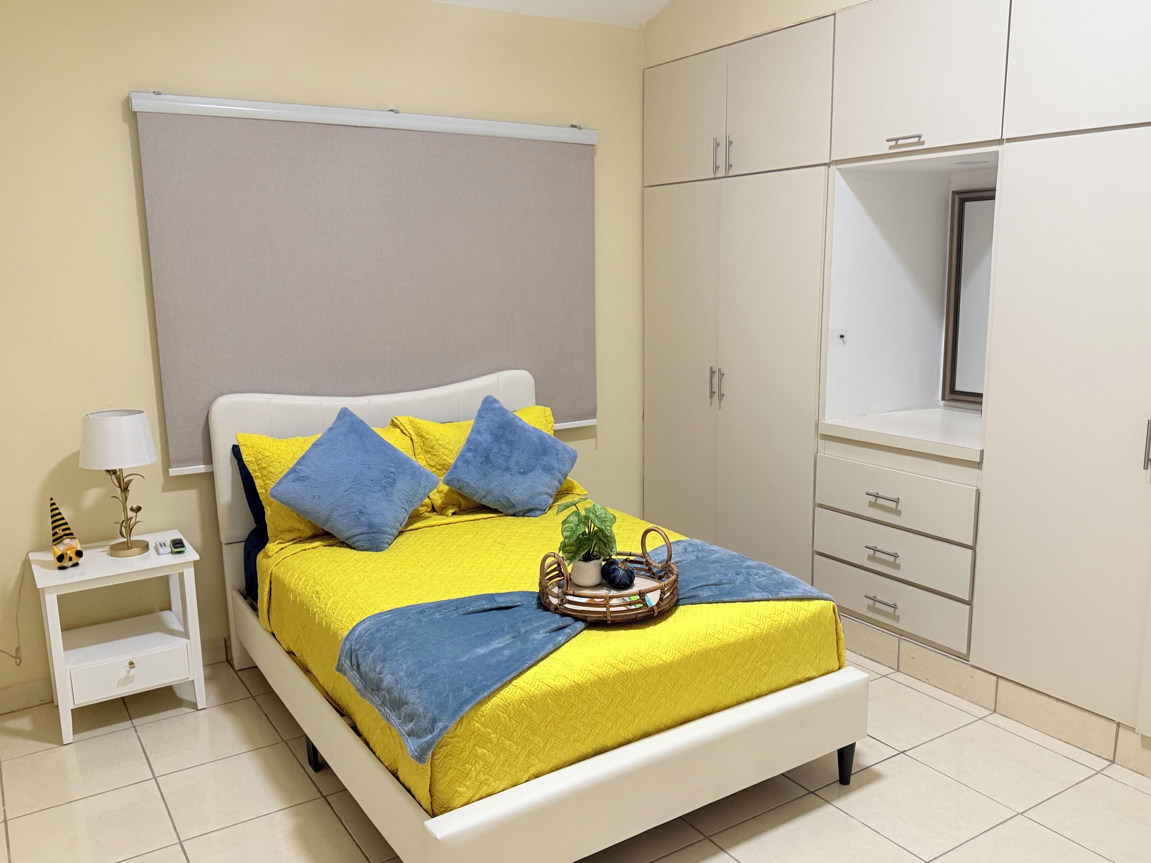 A neatly arranged bedroom with a bed, bedside table, lamp, and wardrobe.