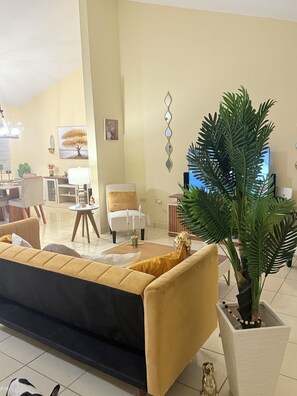 Un salon avec un canapé, une table basse, un fauteuil et une plante en pot.