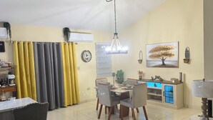 A dining area with a table set for four, a coffee machine, and a yellow curtain.