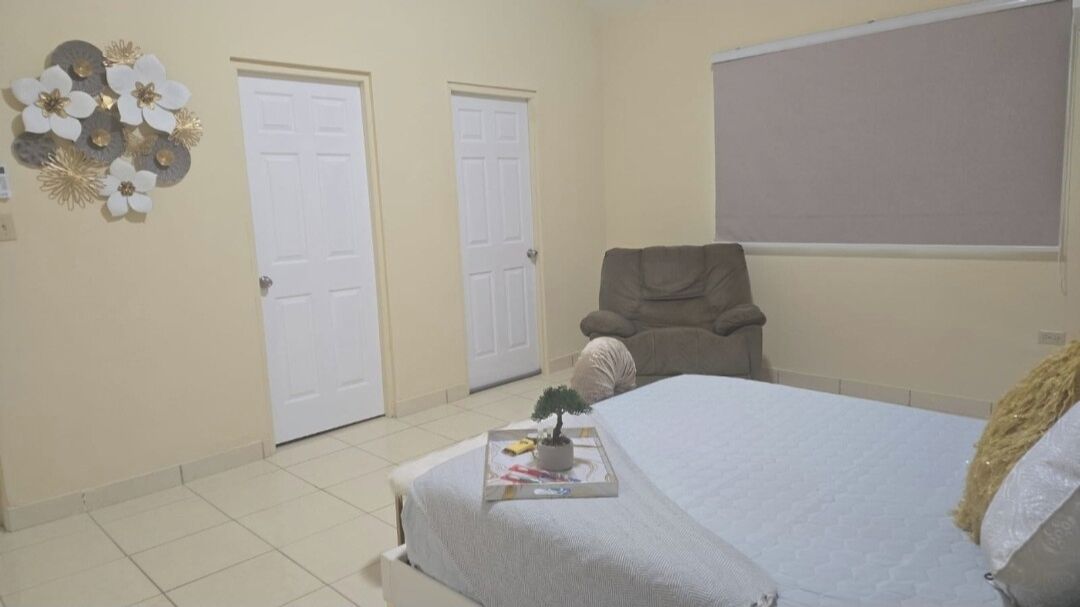 A bedroom with a bed, two doors, a chair, and a wall decoration.