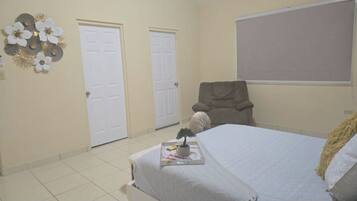 A bedroom with a bed, two doors, a chair, and a wall decoration.