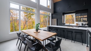Una cocina moderna con ventanas amplias, una mesa de comedor de madera y taburetes negros.