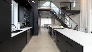 Una cocina moderna con una isla central, una escalera y vistas a un área de estar.