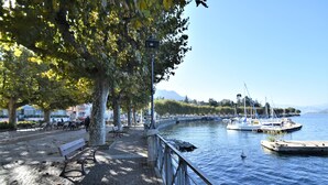 A riverside walkway with benches, a lamppost, and boats docked along the water.