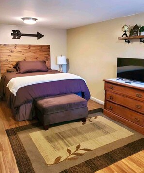 Une chambre avec un lit, une commode, un téléviseur et un panneau indicateur sur le mur.