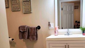 A bathroom with a sink, mirror, towel rack, and a trash can. - Robin's Nest Queen Suite with Private Bath (Saranac Lake)