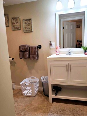 Une salle de bain équipée d’un lavabo, d’un miroir, d’un porte-serviettes et d’une poubelle.