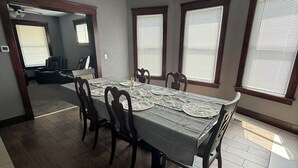 A dining room with a long table, chairs, and a ceiling light fixture. - Newly Renovated Spacious Home! Minutes from cedar point and downtown Sandusky! (Sandusky)