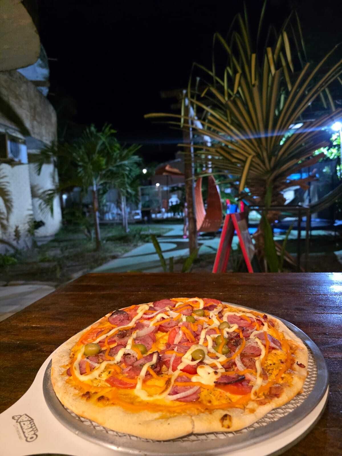 Pizza på et bord med udsigt til en bygning og palmer i baggrunden.