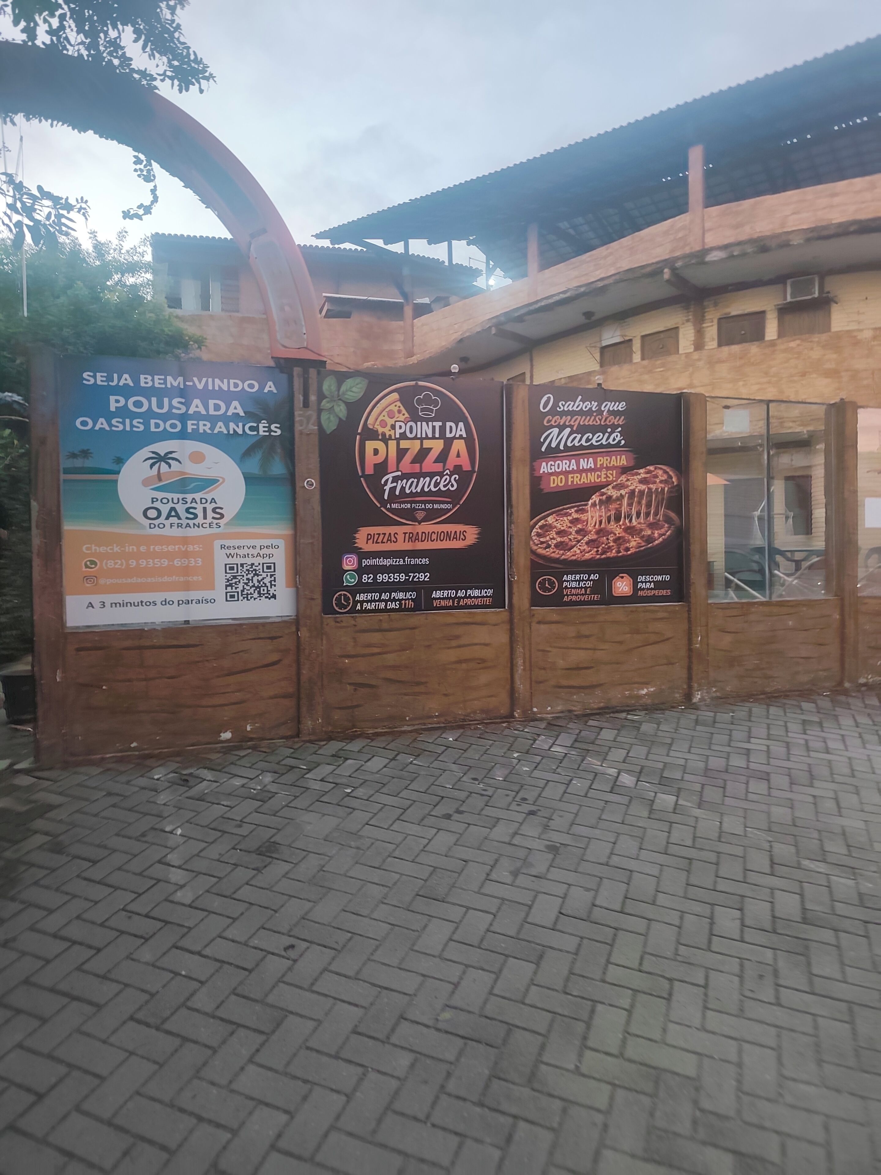 Una estructura de madera con tres anuncios para una pizzería.
