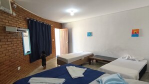 A hotel room with two beds, a brick wall, a window with curtains, and a small painting on the wall. - Pousada Oasis do Francês  (Marechal Deodoro)