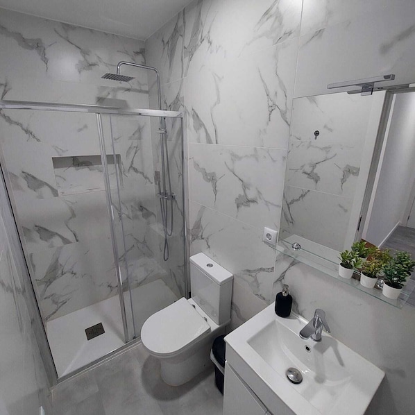 Regadera, secadora de cabello, toallas, papel de baño 
