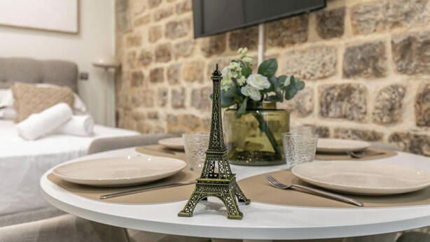 Une table à manger agrémentée d’une pièce maîtresse décorative représentant la Tour Eiffel, d’un vase rempli de fleurs et d’un verre d’eau.