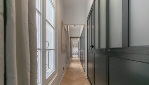 Ein Flur mit Holzboden, einer Tür rechts und einem Fenster links.