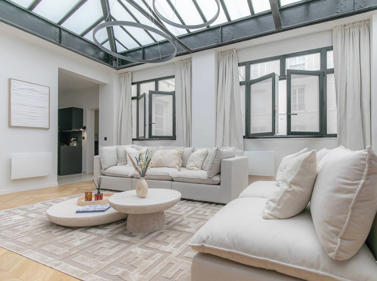 A modern living room with a high ceiling and skylight, featuring a sofa, a coffee table, and a rug.