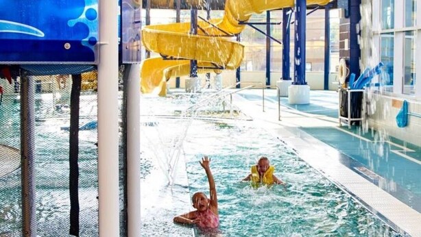 Een overdekt waterpark met meerdere glijbanen en een zwembad.