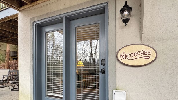 A building entrance with a double door, a wall-mounted sign reading 'NACOCHEE,' and a small electrical box.