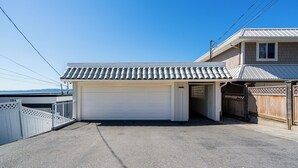 En boligs garage med hvid dør, træhegn og klar himmel.