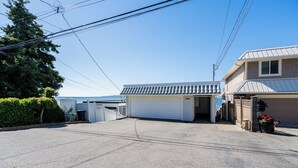 En boliggarage med en ryddelig indkørsel, en indhegnet have og et hus med ståltag.