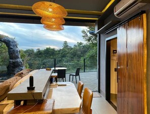A modern dining area with a long table, chairs, and a hanging light fixture. - Mirante Pousada Boutique (Primavera do Leste)