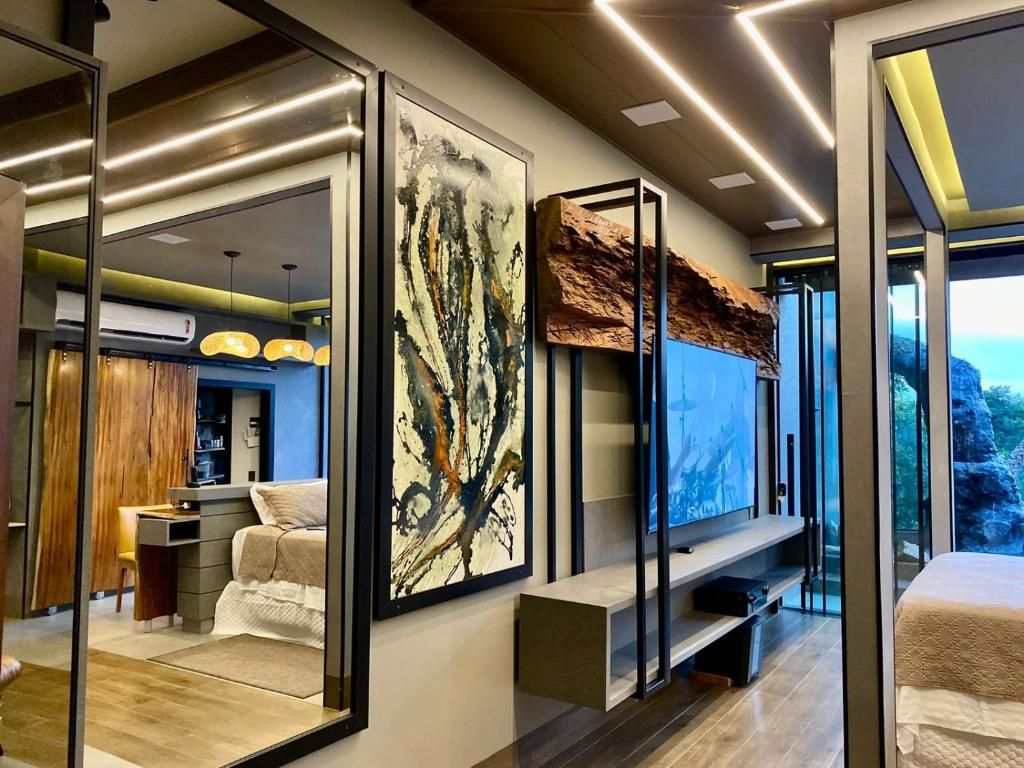 A modern hotel room with a large bed, a seating area, and a large window offering a view of the outdoors.