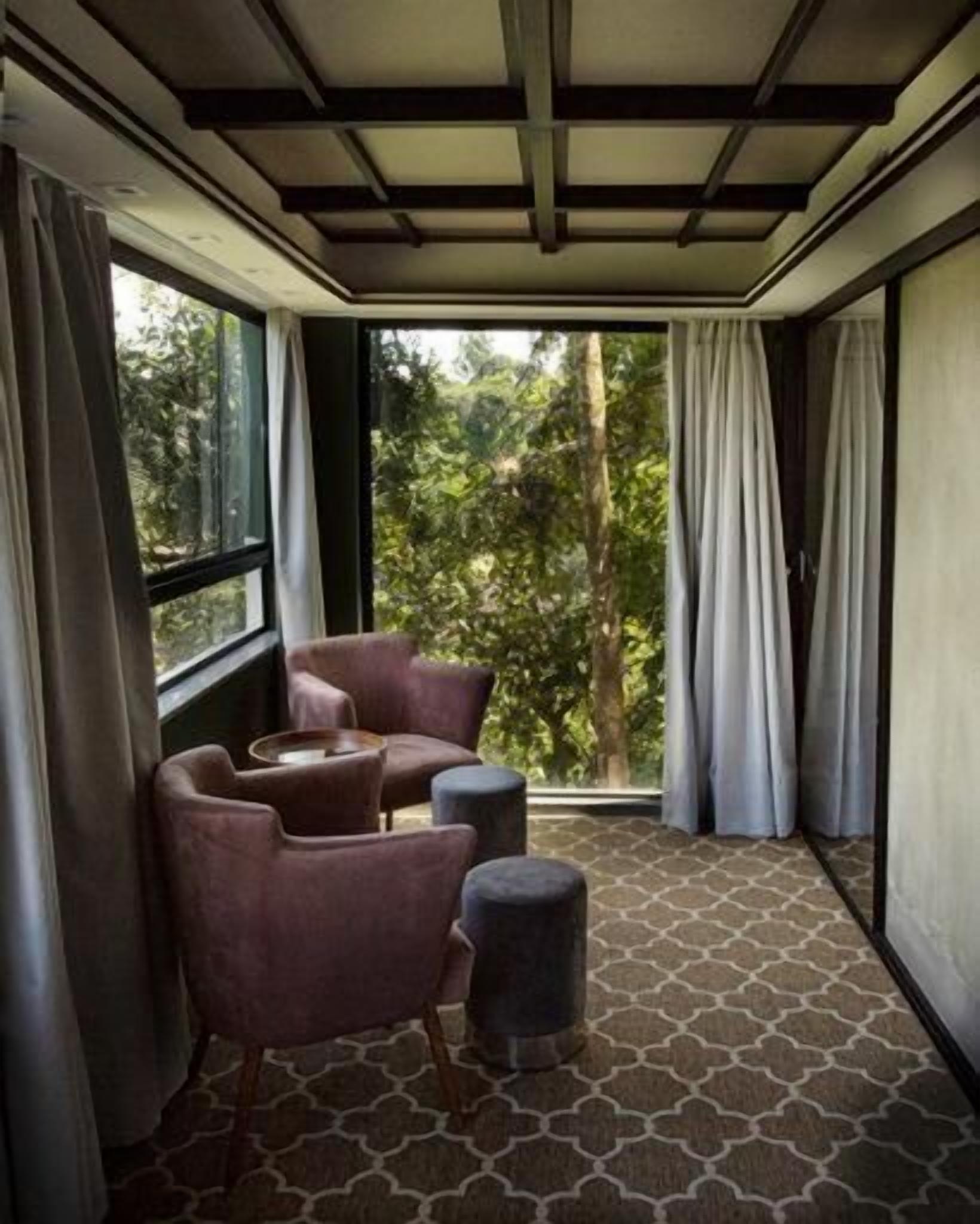 A room with a large window, two chairs, a small table, and a patterned floor.