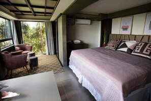 A hotel room with a large bed, a desk, a chair, and a view of the outdoors. - Mirante Pousada Boutique (Primavera do Leste)