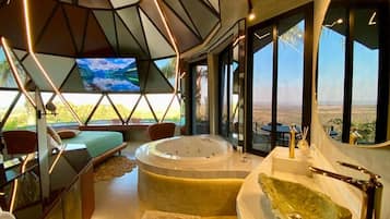 A modern interior with a large bathtub, seating area, and a television.