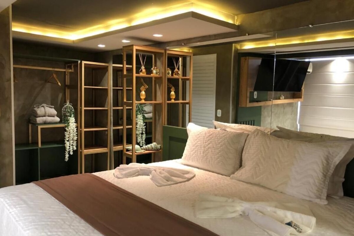 A bedroom with a bed, a wooden wardrobe, and a mirror.