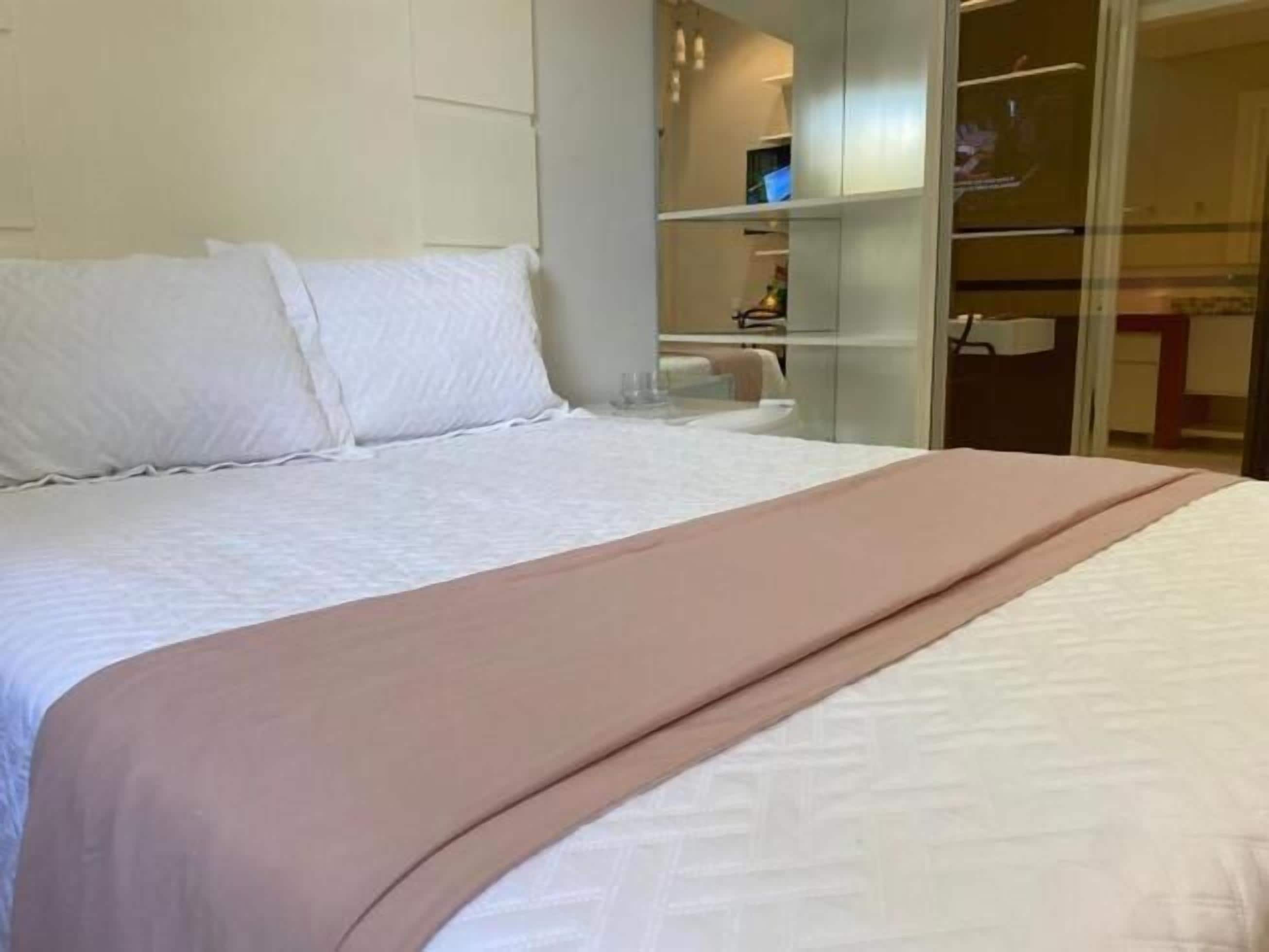 A hotel room with a bed, a bedside table, and a wardrobe.