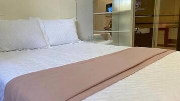 A hotel room with a bed, a bedside table, and a wardrobe.