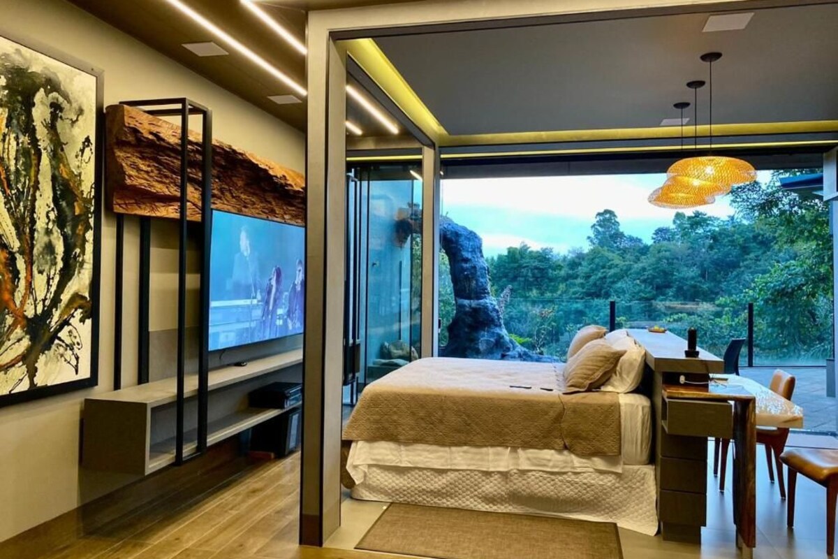 A modern bedroom with a bed, a TV, and a desk with a chair.
