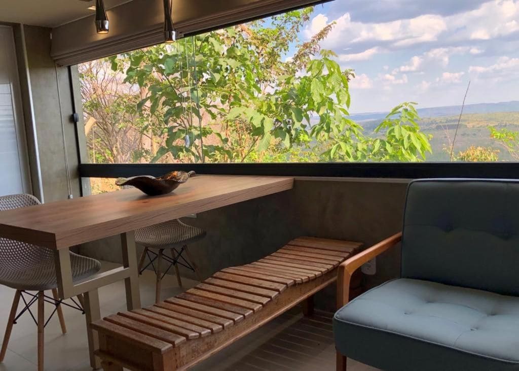 A modern interior with a wooden bench, a table, and a view of greenery outside.