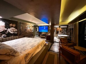 A hotel room with a large bed, a TV, a bathroom, and a seating area. - Mirante Pousada Boutique (Primavera do Leste)