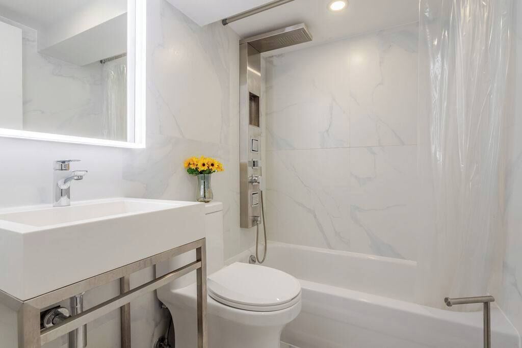 Un baño moderno con un lavamanos blanco, un inodoro y una ducha.