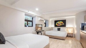 Ett modernt hotellrum med två sängar, ett skrivbord, en TV och en stor tavla på väggen.