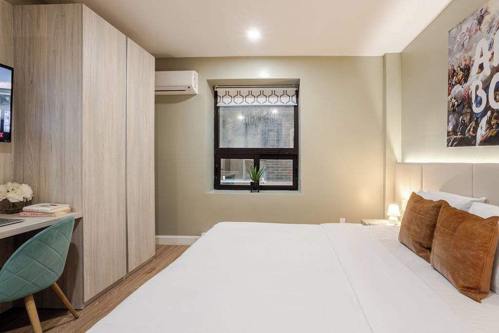 A hotel room with a bed, a desk, and a window with a view.