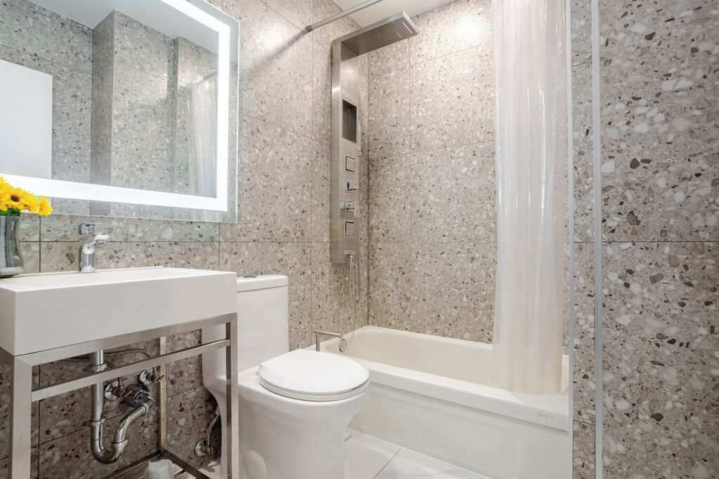 A bathroom with a white sink, mirror, and toilet, and a shower area with a glass door.