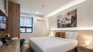 A modern hotel room with a large bed, a desk with a laptop, a TV, and a motivational poster on the wall. - Vibe King – Heart of Montreal (Montréal)
